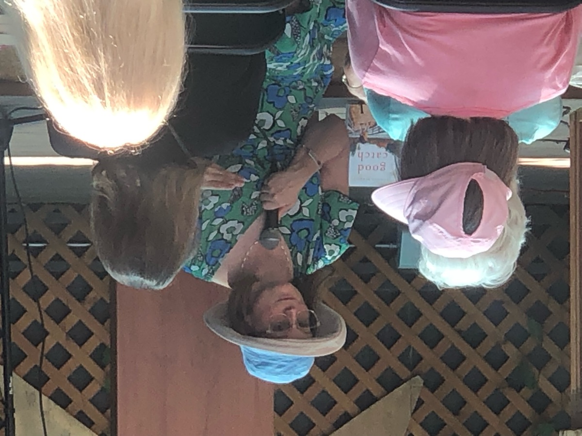 An author in a sun hat and floral dress speaking to the audience.